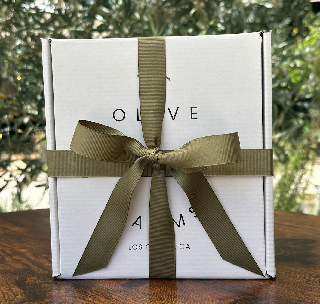 White box with a green ribbon on a wooden surface with a blurred natural background