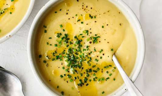 Creamy soup in ramekin with chives, black pepper, and olive oil drizzle for garnish