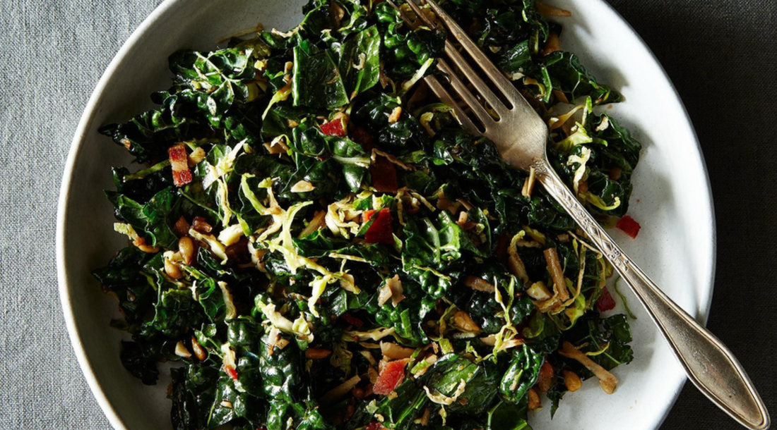 Green leaf kale in a white bowl with a salad fork set on the side.
