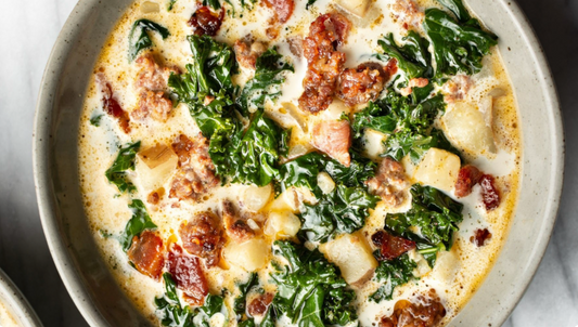 Soup in grey bowl with visible pieces of kale, sausage, and potato.