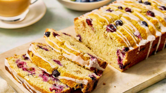 Bread load with blueberries and icing drizzle sliced on cutting board