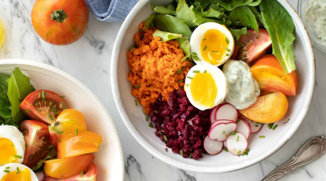 Colorful farmers market breakfast bowl with fresh vegetables, jammy eggs, and a drizzle of olive oil