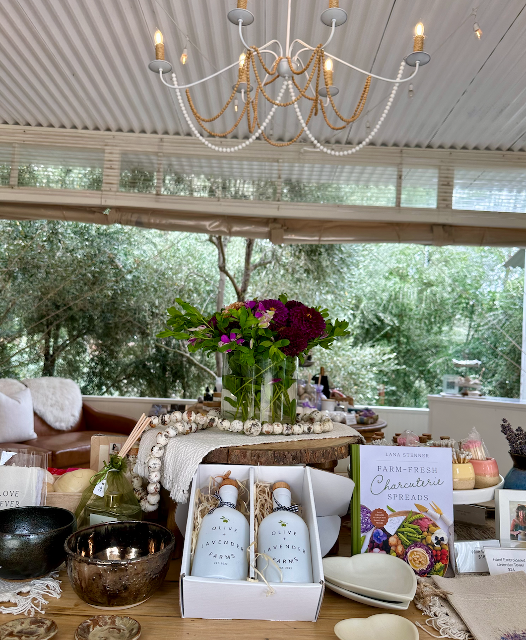 Decorative table setting with bottles, flowers, and a chandelier in a room with large windows.